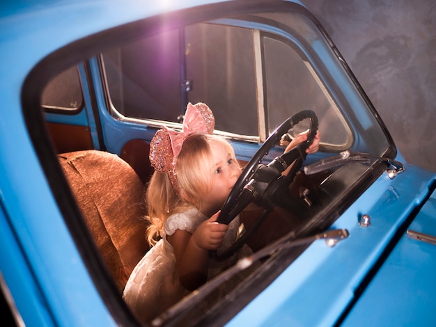 A criança finge o carro da condução que senta-se no assento do motorista dianteiro com mãos na direção.