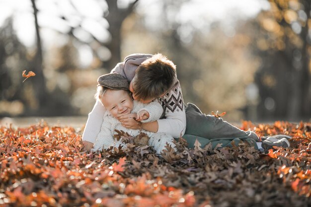 a criança mais velha abraça e se comunica com seu irmão de 6 meses de idade crianças sentadas no parque passam tempo juntos