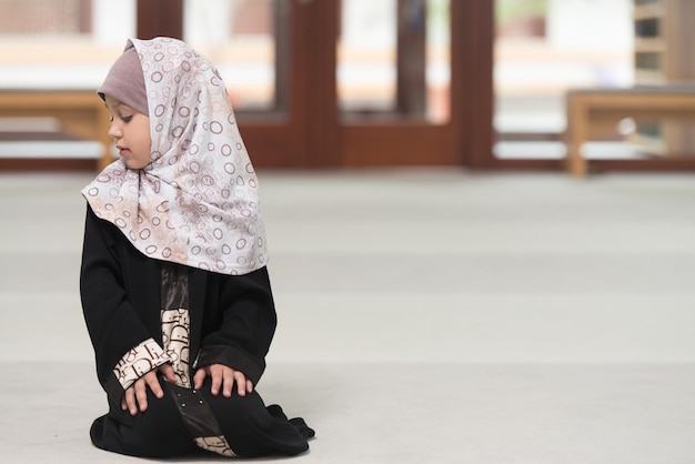 A criança muçulmana humilde está rezando na mesquita