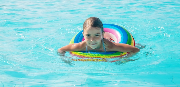 A criança nada e mergulha na piscina. Foco seletivo.