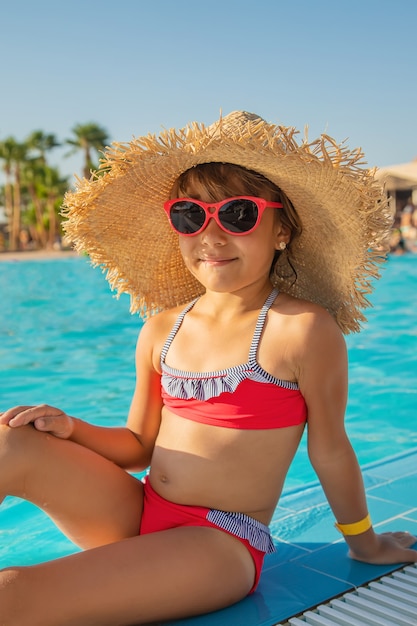A criança nada e mergulha na piscina. Foco seletivo.