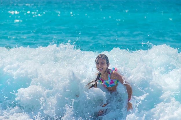 A criança nada no mar sobre as ondas. Foco seletivo. Criança.