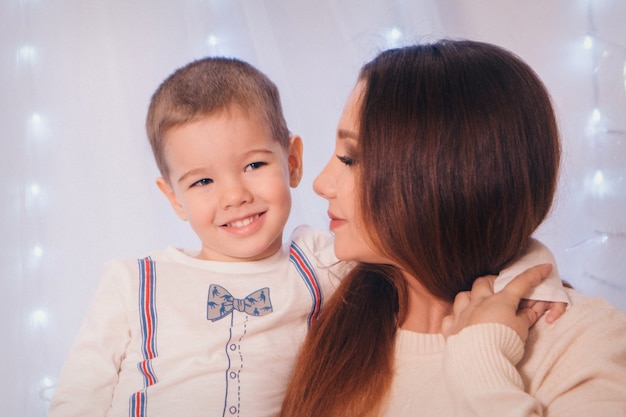 A criança nos braços de sua mãe no fundo de luzes e elementos decorativos