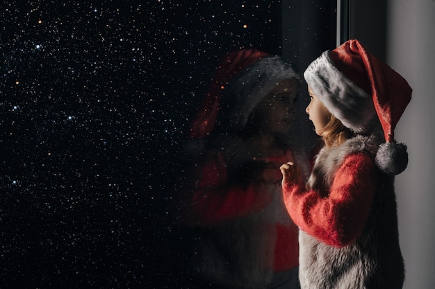 A criança olha pela janela no Natal de Jesus Cristo.