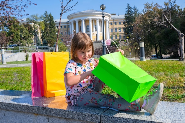 A criança pequena considera compras no parque da cidade em dia ensolarado