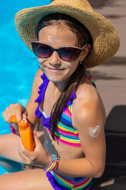 A criança perto da piscina mancha o protetor solar Foco de seleção