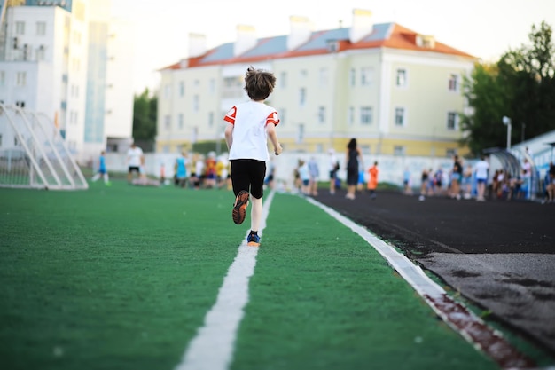 A criança pratica esportes no estádio O menino está treinando antes de jogar futebol