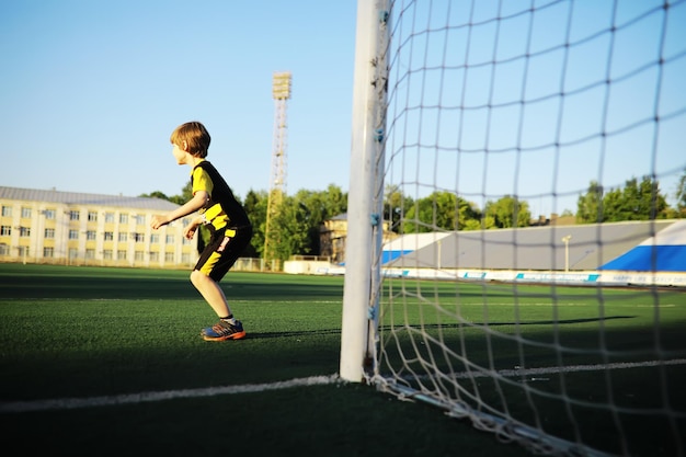 A criança pratica esportes no estádio O menino está treinando antes de jogar futebol