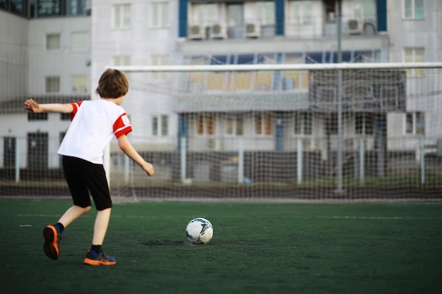 A criança pratica esportes no estádio O menino está treinando antes de jogar futebol