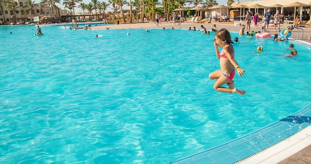 A criança pula na piscina. Foco seletivo.