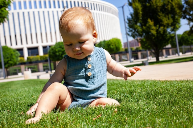 A criança rasteja aprende a rastejar na grama verde no parque no verão