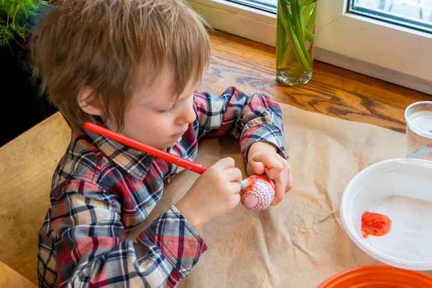 A criança se preparando para a Páscoa Pintar ovos Ovo de tinta vermelha