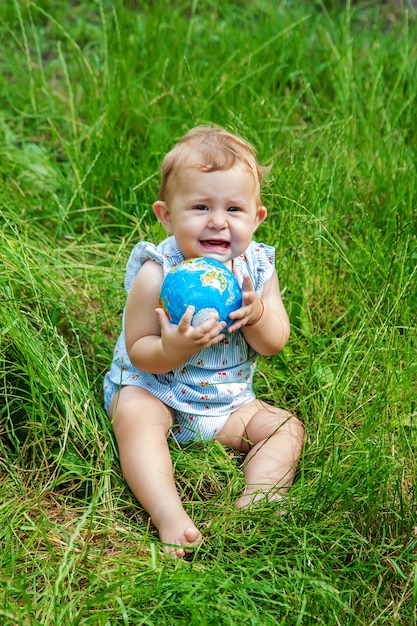 A criança segura o globo nas mãos. Foco seletivo. Natureza.