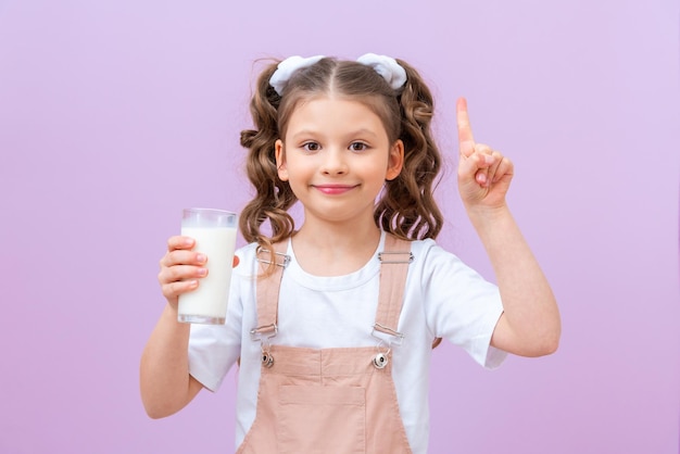 A criança segura um copo de leite e aponta o dedo para seu texto ou anúncio