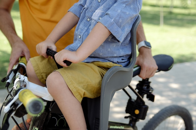 A criança senta-se em uma cadeira de criança em um close de bicicleta