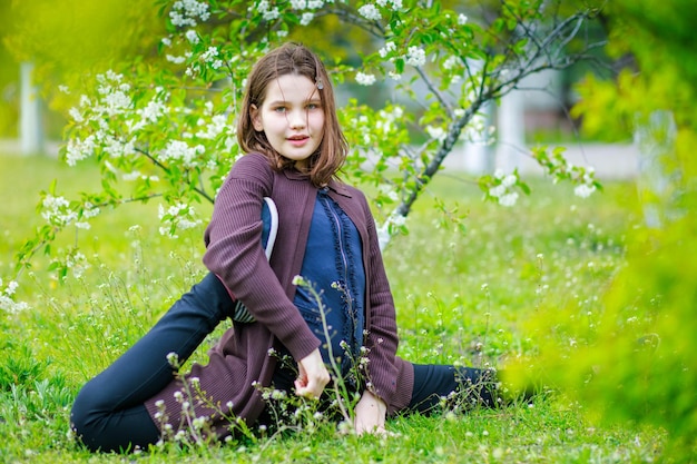A criança sentou-se na corda cruzada Uma garota está se divertindo em um parque de primavera