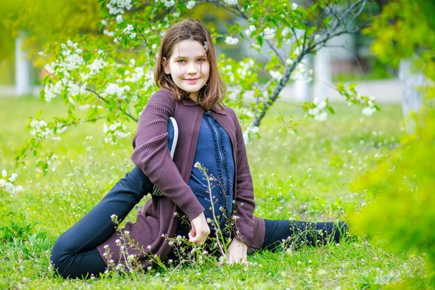 A criança sentou-se na corda cruzada uma garota está se divertindo em um parque de primavera