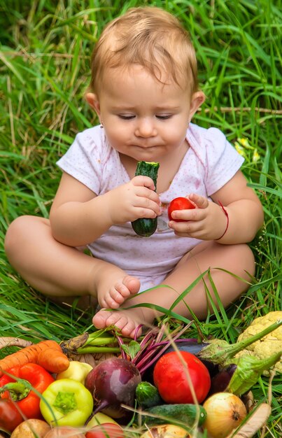 A criança tem vegetais nas mãos. Foco seletivo. Criança.
