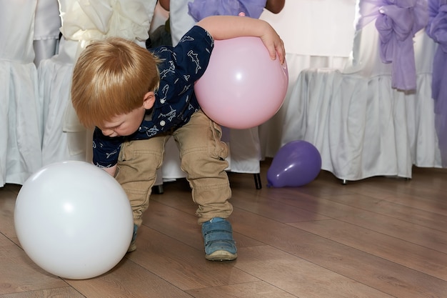 A criança tenta levantar o balão da mesa de banquete crianças em festa em restaurante