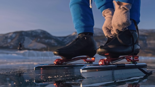 A criança treina na patinação de velocidade no gelo Atleta coloca patins A menina patina no inverno em óculos de esporte sportswear Crianças patinação de velocidade curta longa pista esporte infantil Câmera lenta ao ar livre