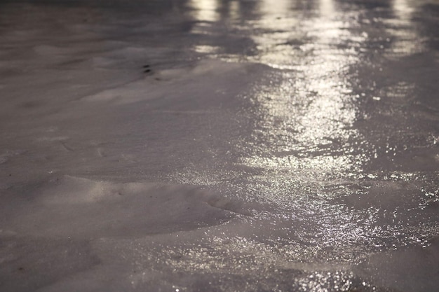 A crosta de gelo brilhante com reflexos de luz cobrindo a neve branca e fria à noite