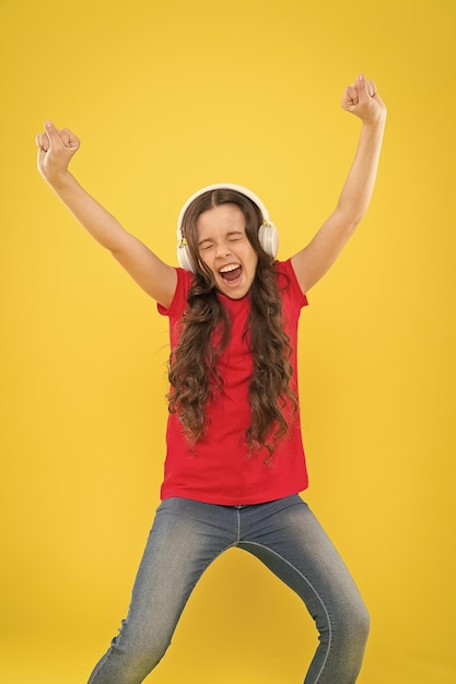 Foto a dança é a poesia do pé pequena dançarina movendo-se para a música em fundo amarelo pequena criança gosta de dançar para a música moderna energética menina bonita dançando com prazer ouvindo música de dança