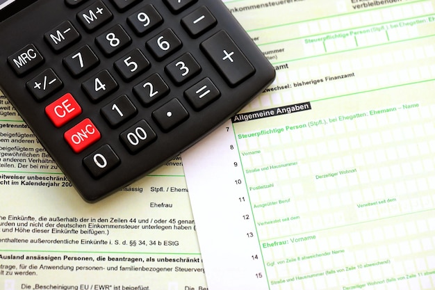 A declaração de imposto de renda anual alemã e a calculadora estão na mesa do contador de perto O conceito de período de pagamento de impostos na Alemanha