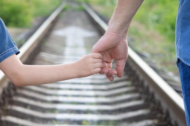 A Die Hände eines glücklichen Elternteils und eines Kindes in der Natur im Reisepark