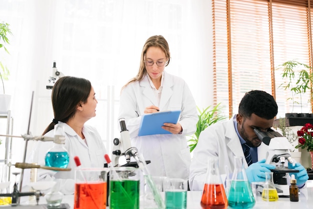 A diversidade de cientistas relata resultados de experimentação para seus colegas no laboratório de pesquisa Grupo de estudantes de química trabalhando no laboratório