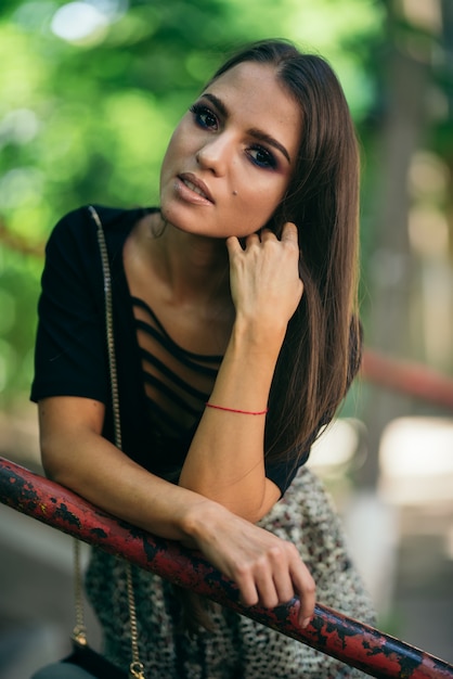 Foto a doce morena sorri e olha a câmera, colocando as mãos no corrimão