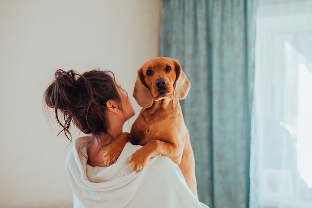 A dona da casa tem nos braços um cachorro, da raça Cocker Spaniel Inglês