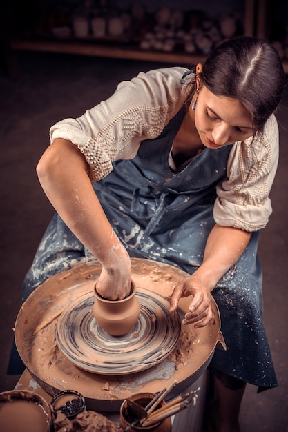 A elegante mestre feminina demonstra o processo de fazer pratos de cerâmica usando a tecnologia antiga. Fazer pratos de cerâmica.