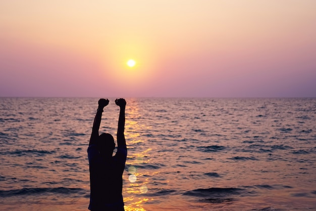 A elevação do homem entrega até o conceito da liberdade do céu com céu azul e fundo da praia do verão.