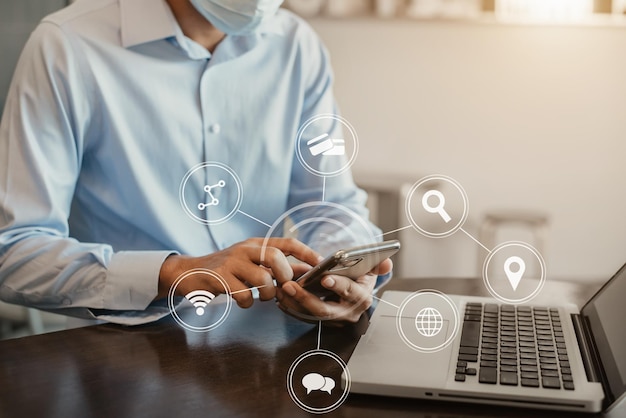 A empresa masculina está usando um telefone celular e um laptop pela manhã.