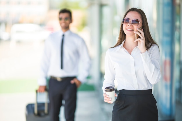 A empresária segurando uma xícara de café e telefone perto do homem