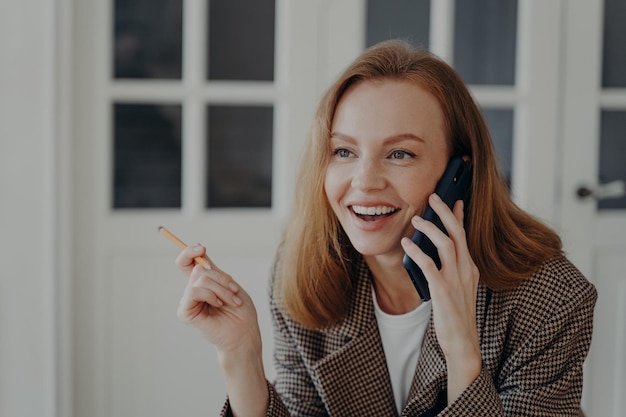 A empresária tem um telefonema e uma mulher elegante e feliz de meia idade está trabalhando em casa