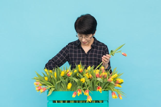 A encantadora florista morena separa as tulipas da caixa e as seleciona para a futura flor