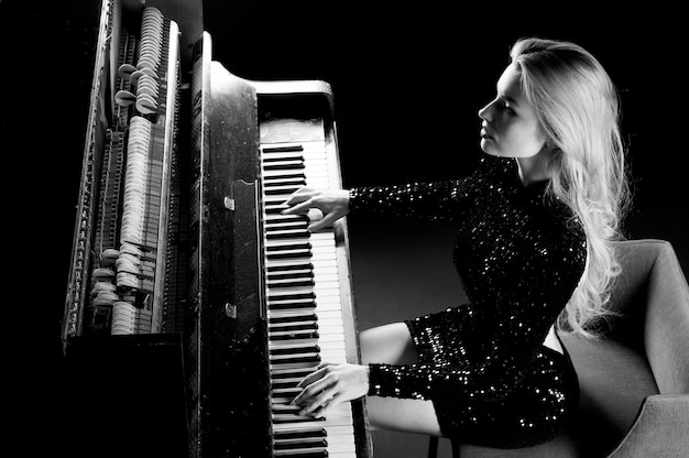 A encantadora garota em um vestido de noite toca o velho piano alemão. Vista de cima. Mídia conceitual