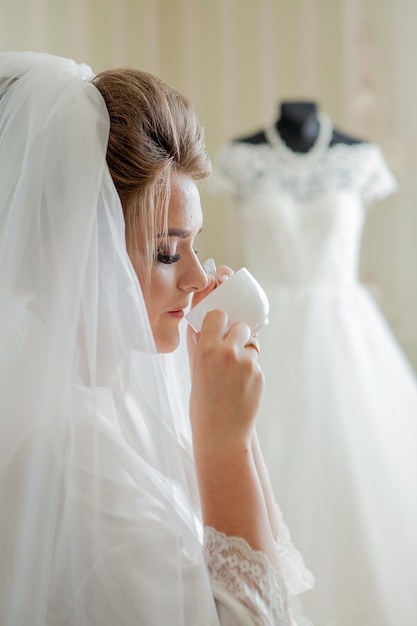 A encantadora noiva com damas de honra perto do vestido de noiva