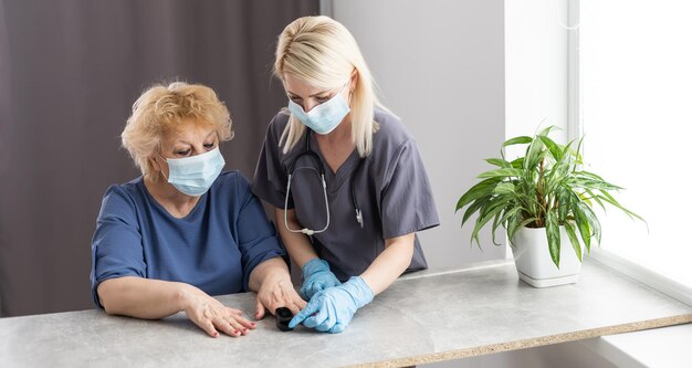 A enfermeira usa um oxímetro de pulso para medir a saturação de oxigênio no sangue de um paciente idoso.