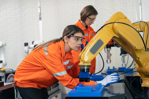 A engenheira verifica e controla a máquina de braços robóticos de automação em uma fábrica inteligente industrial em tempo real, robótica de software de sistema de monitoramento e operação de fabricação digital