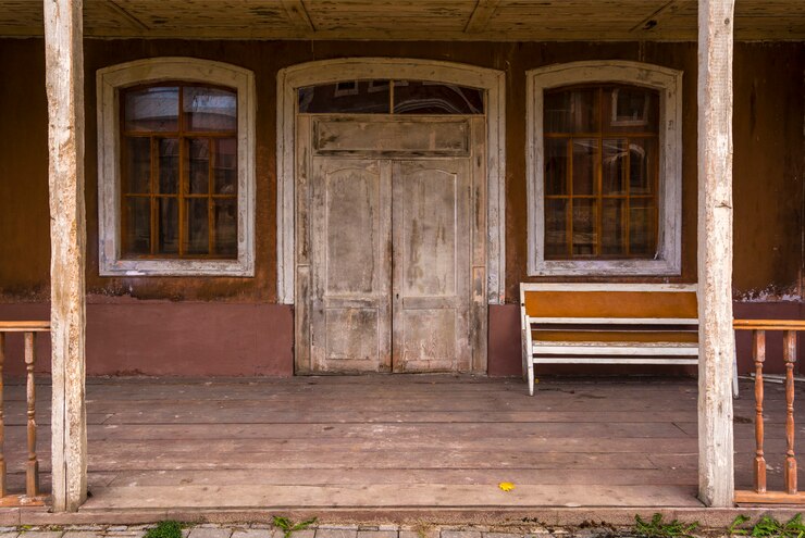Foto a entrada para a antiga casa de madeira, o antigo sofá está na varanda.