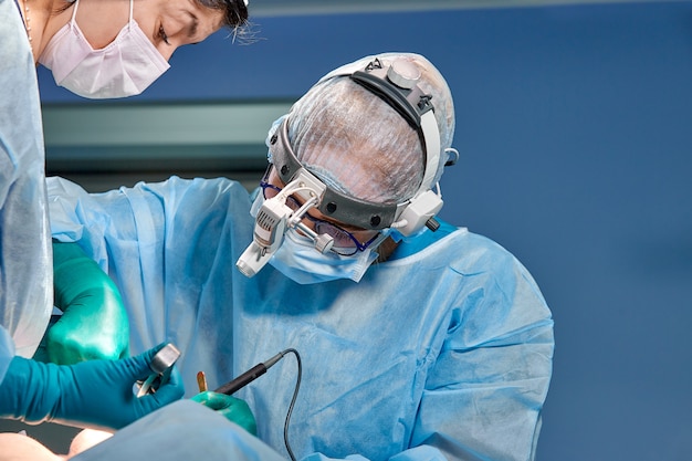 A equipe de cirurgiões faz uma operação invasiva. Retrato de close-up de cirurgiões. Trabalhar com um instrumento de coagulação, coagulação vascular