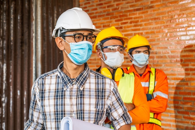 A equipe de engenheiros de construção e três arquitetos estão prontos para usar máscaras médicas. corona ou covid-19 usam máscaras durante o projeto de construção.