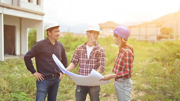 A equipe de engenheiros discute e trabalha no canteiro de obras. Inspeção no projeto da vila e na construção da propriedade.