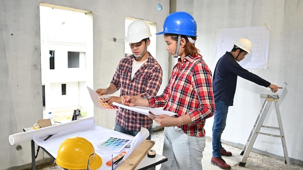 A equipe de engenheiros discute e trabalha no canteiro de obras. Inspeção no projeto da vila e na construção da propriedade.