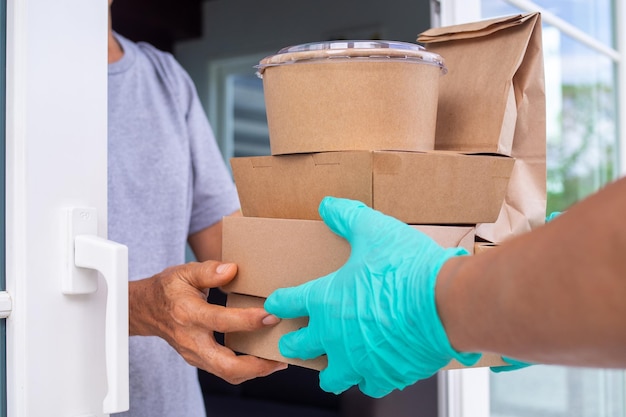 A equipe de entrega de alimentos usa luvas para evitar germes durante a entrega de alimentos aos clientes