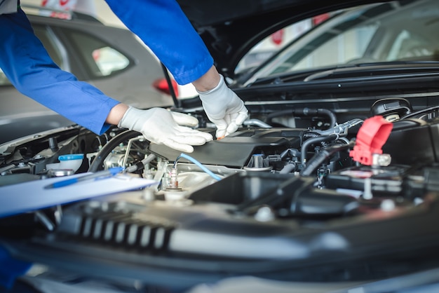 A equipe do mecânico de automóveis está puxando o medidor de nível de óleo para cima para verificar o nível de óleo. Para verificar a condição do carro