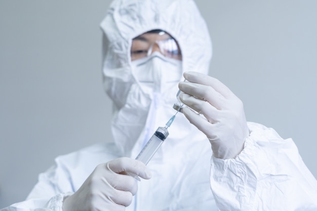 Foto a equipe médica do epi usa seringas e vacinas para o tratamento do vírus covid-19. pesquisadores médicos do laboratório estão testando vacinas para o tratamento de doenças virais.