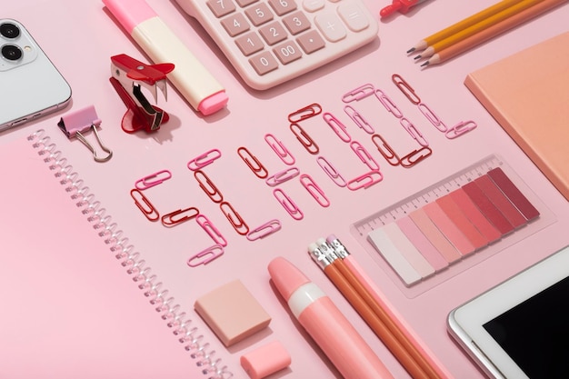 A escola de inscrição de clipes de papel em um fundo rosa com material escolar